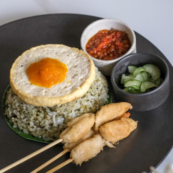 Vegan pesto fried rice topped with tofu egg, soy-based chickun skewer, served with pickles and sambal from Sauce Tree Bali