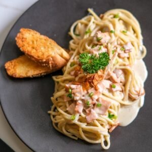 Creamy vegan carbonara pasta with soy-based smoked hum and coconut bacon, made with cashew and plant milk sauce from Sauce Tree Bali